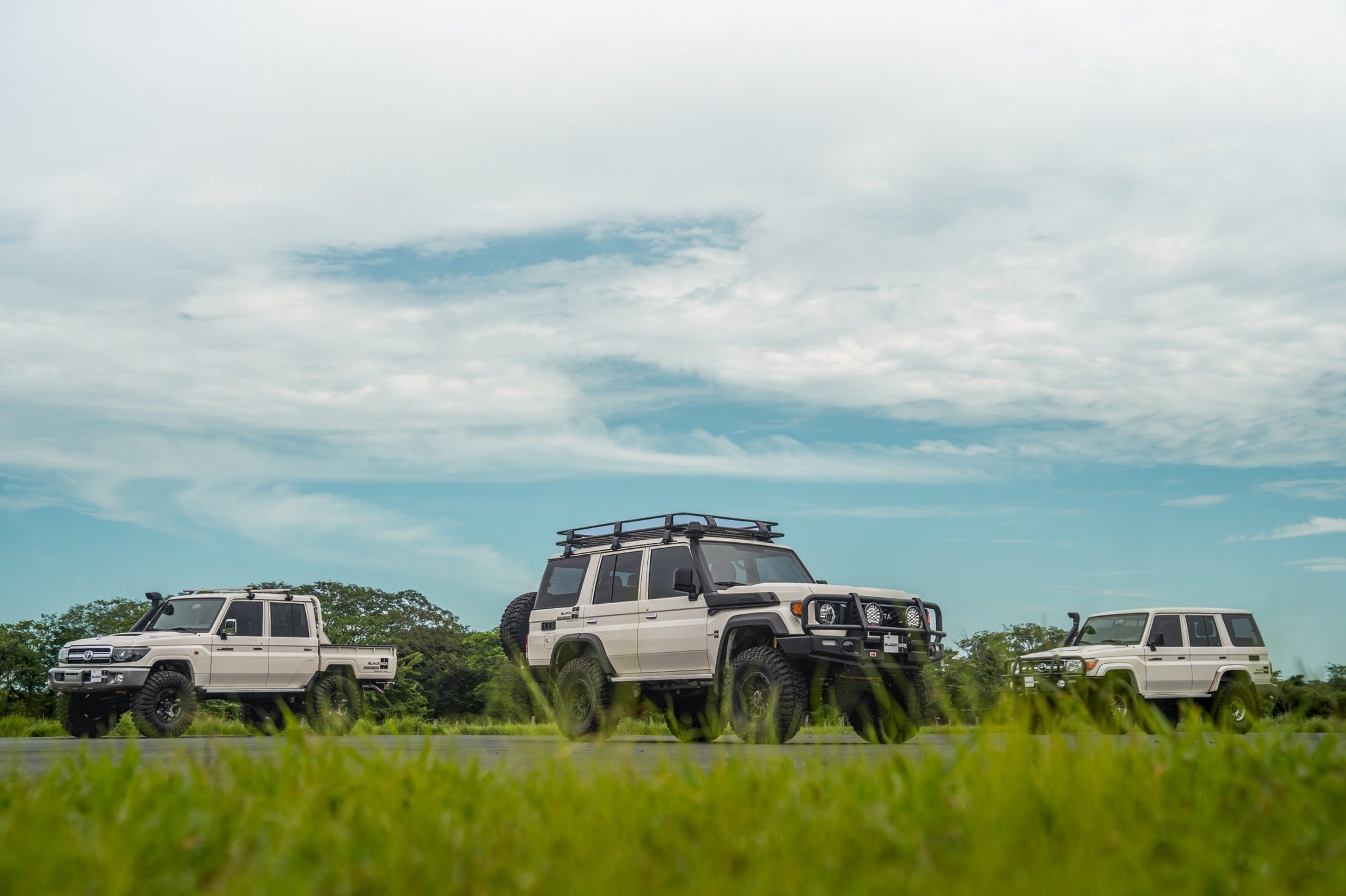 Three Toyota Land Cruiser 70s filmed from a low angle under a wide sky, photographed by Maxime Hugo