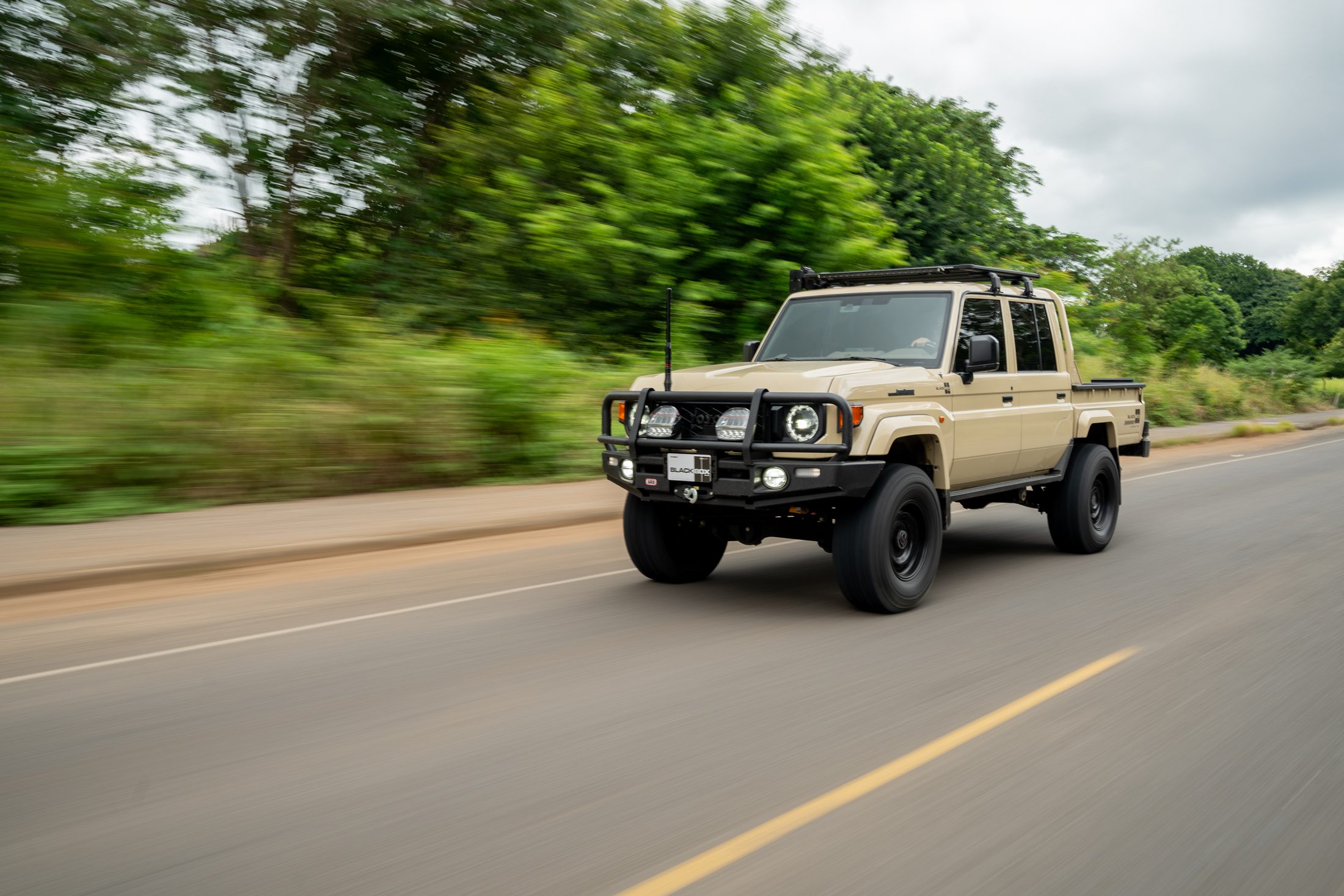 Beige Toyota Land Cruiser 70 pickup, rolling shot with motion blur, photographed by Maxime Hugo