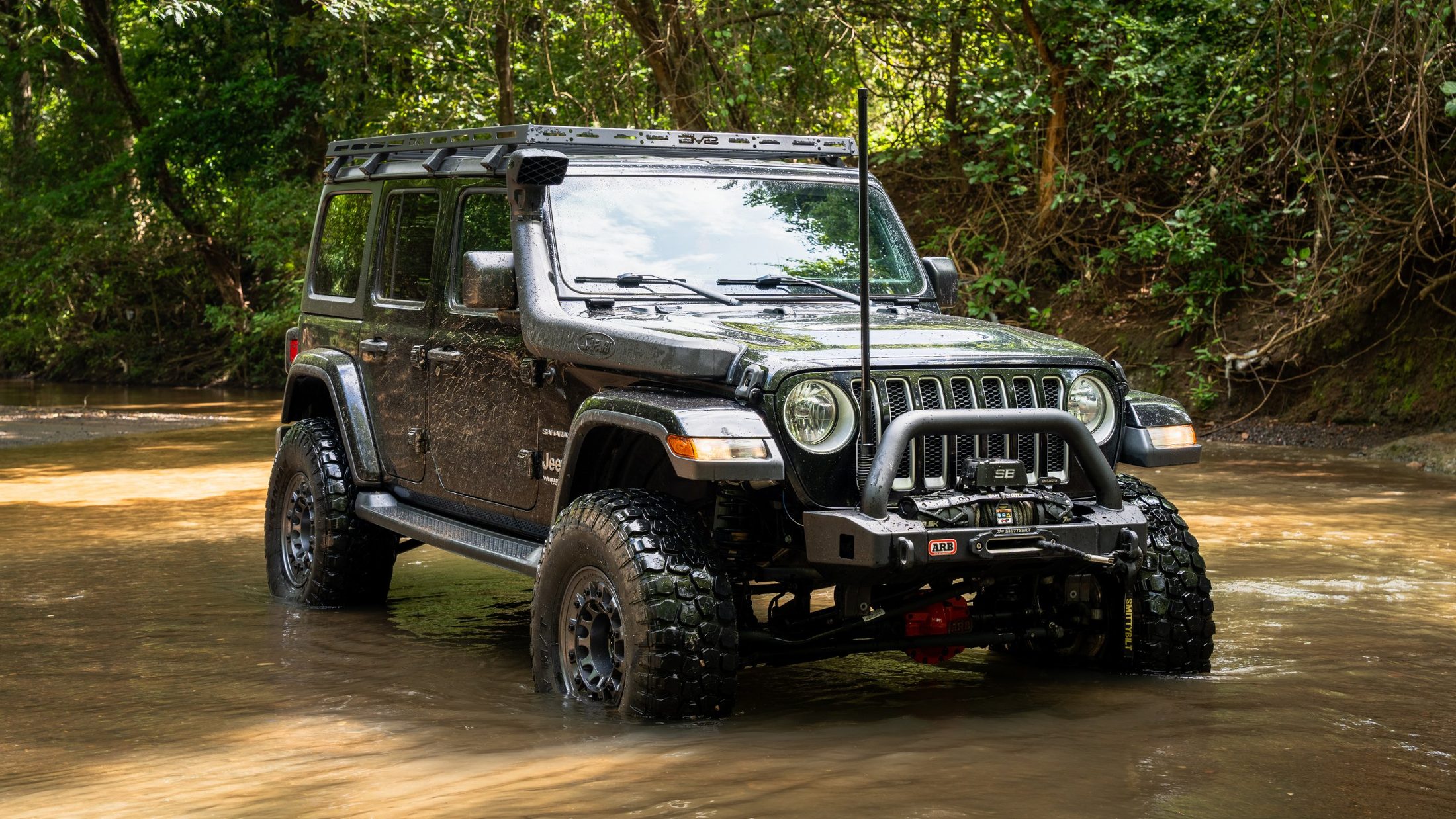 Black Jeep Wrangler standing in a shallow river, photographed by Maxime Hugo