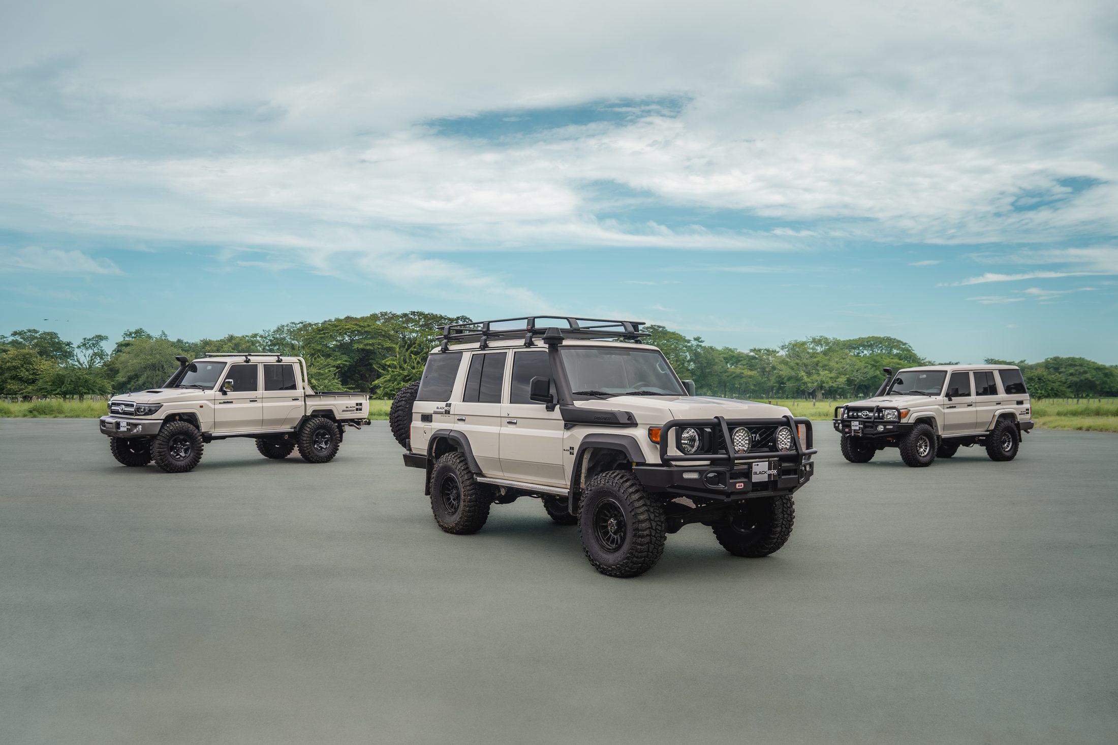 Three BlackBox 4x4 Land Cruiser 70s on an open tarmac apron, photographed by Maxime Hugo