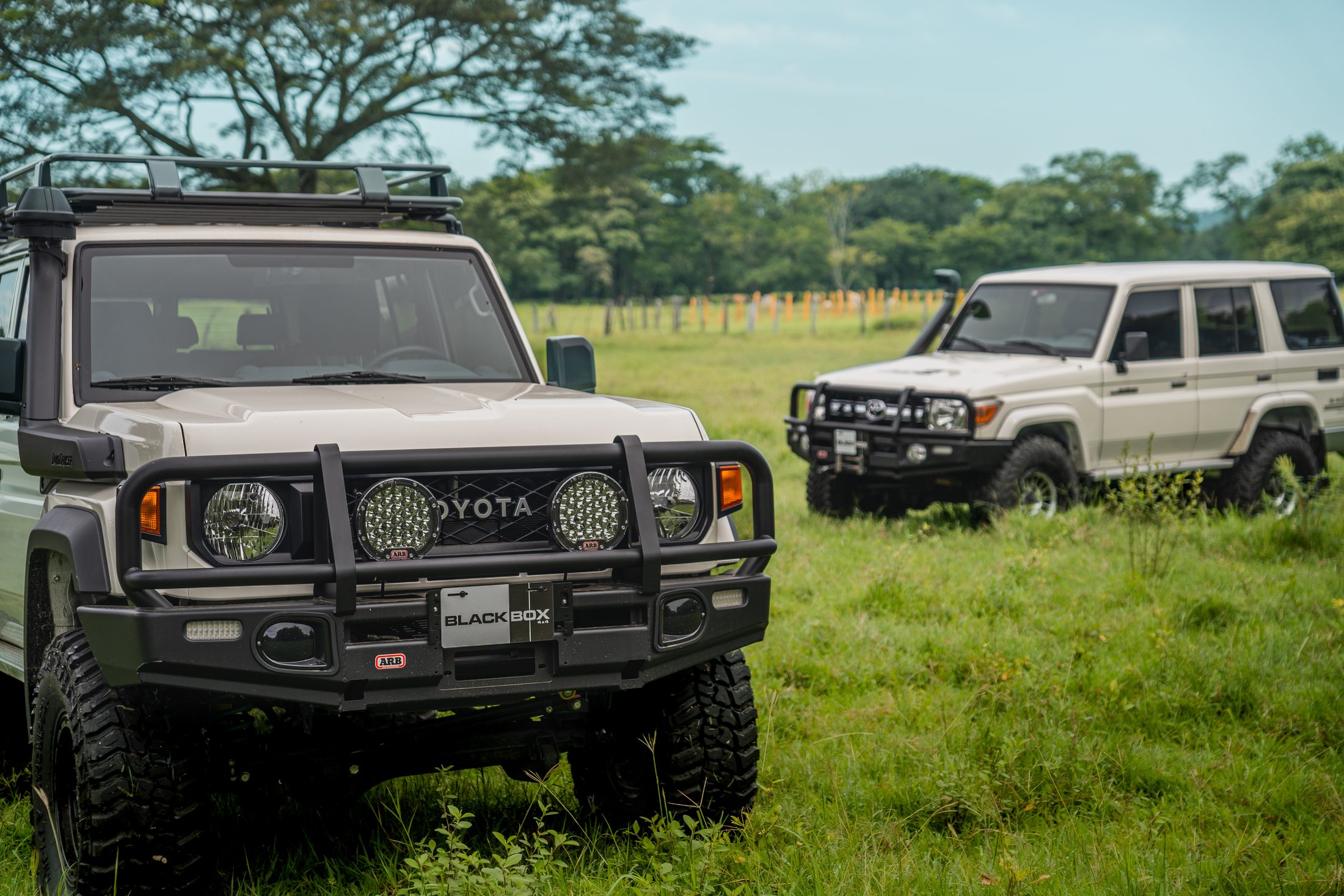 Front of a white Land Cruiser 70 with ARB lights, second truck behind, photographed by Maxime Hugo