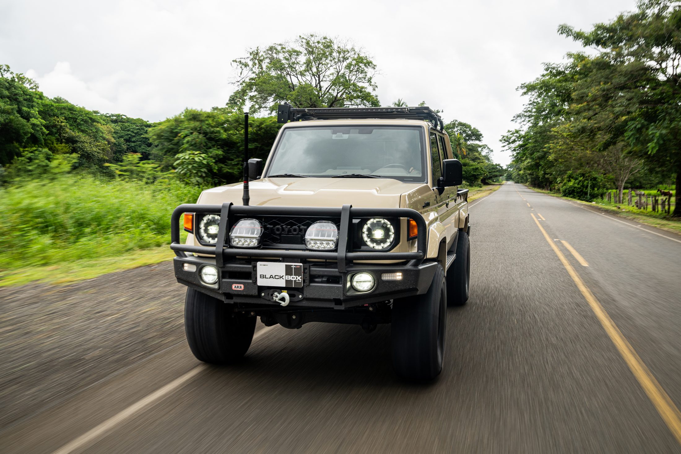 Beige Toyota Land Cruiser 70 head-on, rolling shot on an open road, photographed by Maxime Hugo